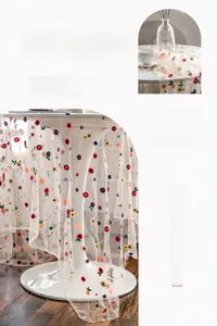 Close-up of white lace tablecloth with colorful floral embroidery on mesh fabric