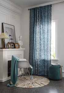 Detail of bohemian blue geometric print curtain with black fringe tassels and linen texture