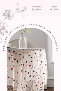 Detailed close-up of white lace tablecloth with vibrant floral embroidery and mesh texture