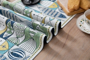 Close-up detail of green and blue jacquard table runner with fish pattern and woven texture