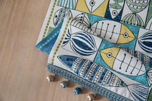 Detail of jacquard table runner with abstract fish pattern and beaded fringe tassels