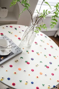 Close-up of white lace tablecloth with colorful floral embroidery and smooth fabric texture