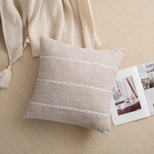 Detail of oatmeal linen pillow cover with white woven embroidery lines and textured fabric