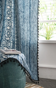 Detail of blue bohemian geometric curtain with cotton linen texture and black tassel fringe