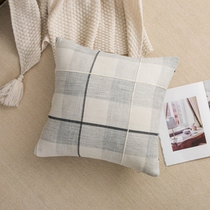 Detail of grey and white plaid cushion cover with natural linen texture on a soft rug