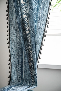 Detail of blue geometric print bohemian curtain featuring elegant black tassel edges