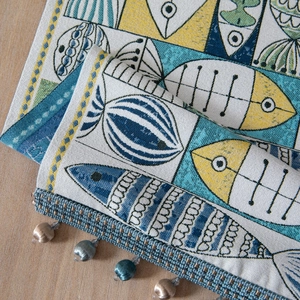 Green and blue jacquard table runner with fish patterns and beaded tassel fringe