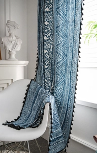 Detail of blue geometric curtains with black tassels and matching bohemian fabric