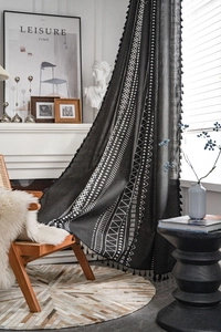 Dettaglio di tenda bohémien in cotone lino nero con motivi geometrici bianchi e nappe