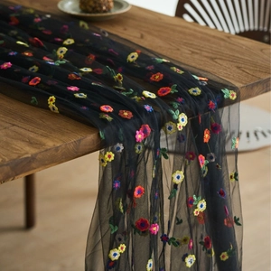 Macro detail of colorful floral embroidery on high-quality black mesh fabric for table decor