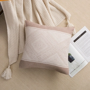 Detailed close-up of brown geometric jacquard cushion cover on a soft cream rug