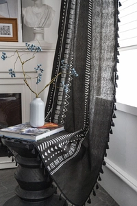 Dettaglio di tenda in cotone lino nero con motivo tribale e eleganti frange nere