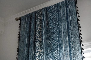 Detail of blue and white geometric print curtain with stylish black tassel fringe trim