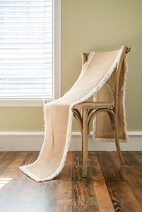 Detailed texture of natural jute table runner with cream tassels on a vintage wooden chair