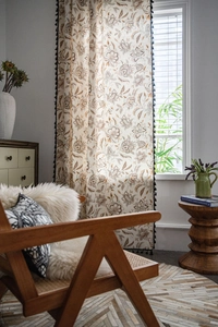 Detail view of floral print curtains with decorative black tassels and linen texture