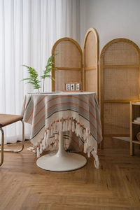 Close-up of striped Nordic tablecloth with tassels on a round table in natural light