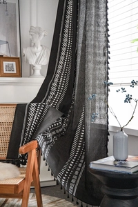 Dettaglio di tenda in lino con motivi geometrici in bianco e nero e frange nere eleganti