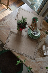 Detail of woven jute placemat with tassels on a rustic wooden table for dining