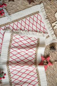 Detail of red diamond pattern embroidery and fringe tassels on a woven jute placemat