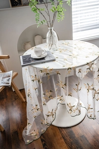 Close-up of yellow floral embroidery on white lace tablecloth with green wavy edges