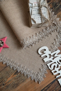 Detail of vintage jute table runner with delicate lace embroidery and fringe texture