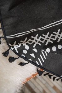 Dettaglio di tessuto in lino con motivi geometrici bianchi e neri e morbide nappe