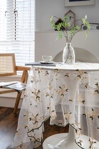 Detail of French floral embroidery on white lace tablecloth with scalloped green edge