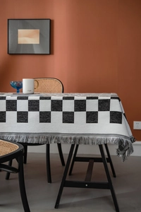 Detail der karierten Tischdecke mit schwarz-weißem Muster und Baumwollfransen an den Kanten