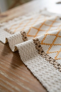 Close-up detail of bohemian cotton linen table runner with orange diamond embroidery