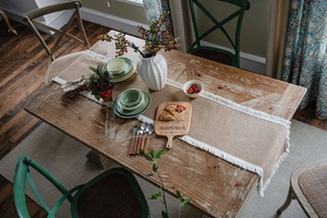 Detail of natural jute table runner featuring delicate white fringe tassels and rustic weave