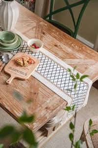 Dettaglio runner da tavola in cotone e lino intrecciato a mano con rombi e nappe nere