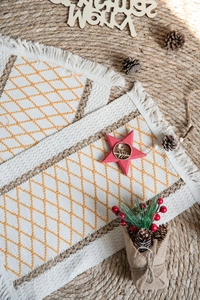 Detail of bohemian cotton table runner with yellow diamond embroidery and tassel fringe