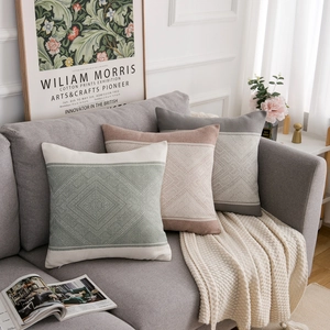 Modern geometric knitted throw pillows in pink and green on a sofa in a cozy living room