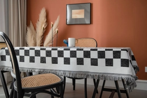 Detailansicht der schwarz-weißen Tischdecke mit Schachbrettmuster und dicken grauen Fransen