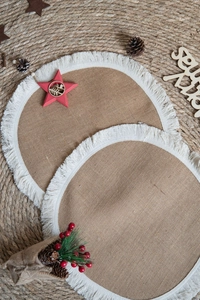 Close-up of circular natural jute placemats with dense white fringes and holiday decor