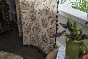 Detail of vintage floral pattern and black tassels on rustic linen curtains