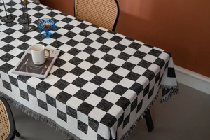 Detailaufnahme der schwarz-weiß karierten Tischdecke mit eleganten grauen Fransen am Rand