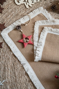 Detail of natural jute placemat with white fringe tassels on rustic woven table runner