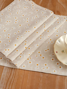 Close-up of cotton linen placemat featuring white daisy prints on a beige background