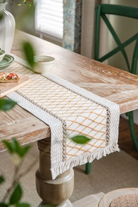 Macro detail of bohemian cotton linen table runner with geometric diamond patterns and tassels