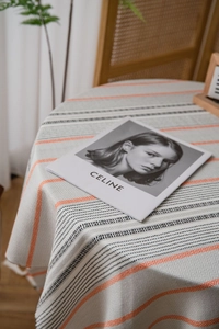 Detail of Nordic style tablecloth with herringbone weave and orange stripe on round table