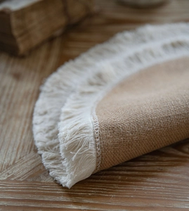 Close-up of natural jute table runner with white fringe trim on a vintage wooden desk
