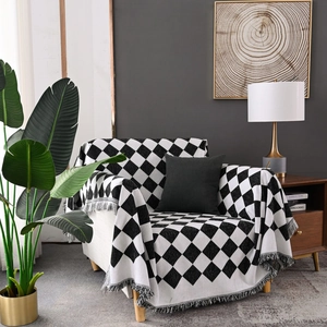 Moderne schwarz-weiße karierte Wohndecke mit grauen Fransen auf einem Sofa drapiert
