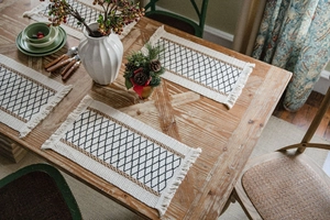 Detailed view of bohemian woven placemats with black diamond patterns and elegant fringes