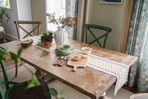 Detail of cotton linen table runner with woven tassels and geometric pattern on wood table