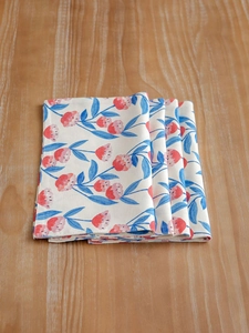 Macro detail of cotton linen placemats featuring pink floral prints on a wood table