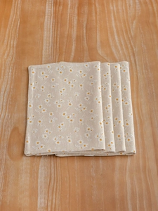 Detail of four-piece set cotton linen placemats with daisy print on a wooden table