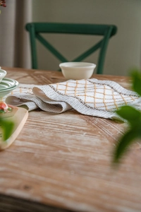 Detailed embroidery of yellow and brown diamond patterns on cotton linen table runner