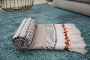 Close-up of Nordic woven tablecloth with orange wave patterns and handmade white tassels