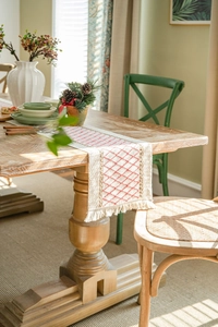 Detail of cotton linen table runner featuring red diamond embroidery and handmade tassels